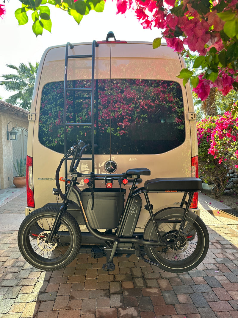 RadRunner e-bike mounted on a beige Mercedes-Benz Sprinter RV rental van, parked on a brick driveway amidst vibrant pink bougainvillea. — photo 23