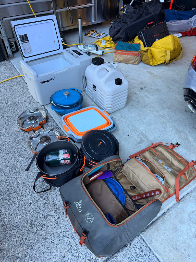 Essential gear for an rv rental trip: A portable fridge, camping stoves, water container, and kitchen organizer are laid out. — photo 16
