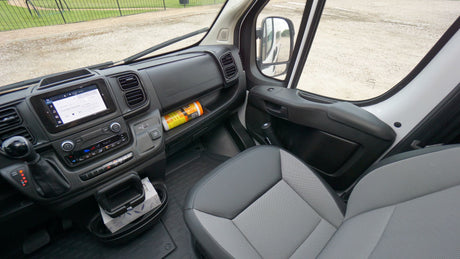 Spacious RV rental van interior: dashboard with large touchscreen, climate controls, gear shifter, and passenger seat.
