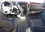 Interior view of a Mercedes-Benz van for RV rental, showing the dashboard, steering wheel, console, and front seats.
