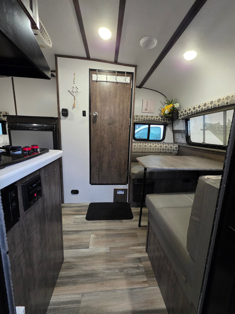 Modern RV rental interior with a functional kitchen, cozy dinette, and light wood flooring, ready for adventure. — photo 1