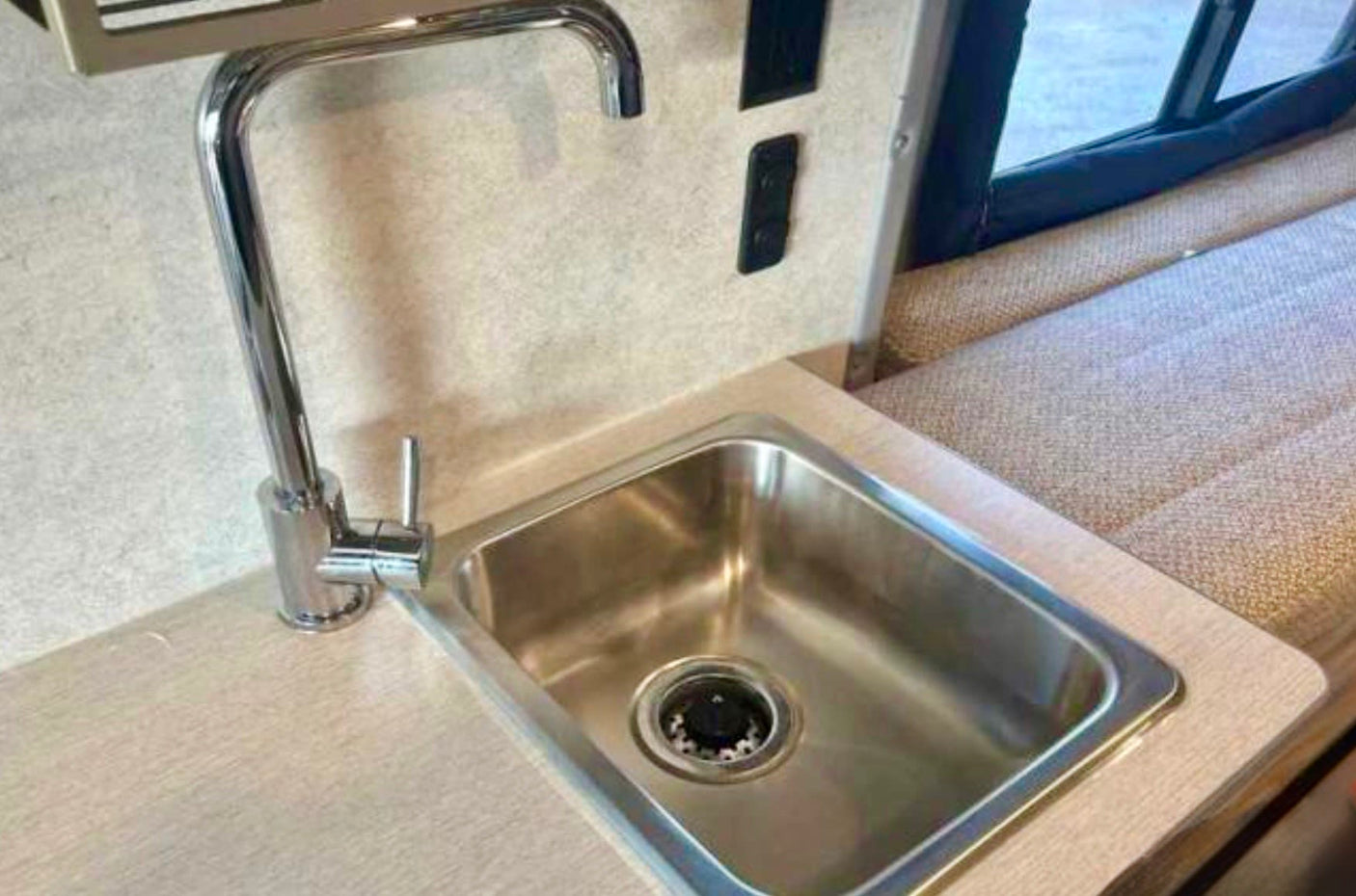 Compact kitchenette in an RV rental, featuring a stainless steel sink and chrome faucet. Ideal for travel and camping.