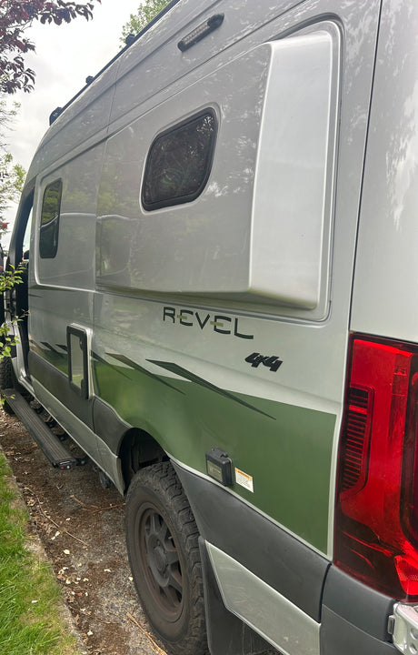 Explore in style! This silver Winnebago Revel 4x4 camper van, featuring a green graphic wrap, is ready for your next RV rental adventure.