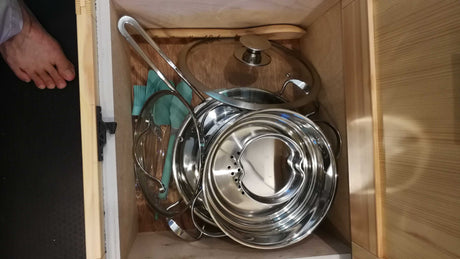 Inside an RV rental drawer: compact kitchenware, including stainless steel pots, glass lids, and utensils for efficient cooking.