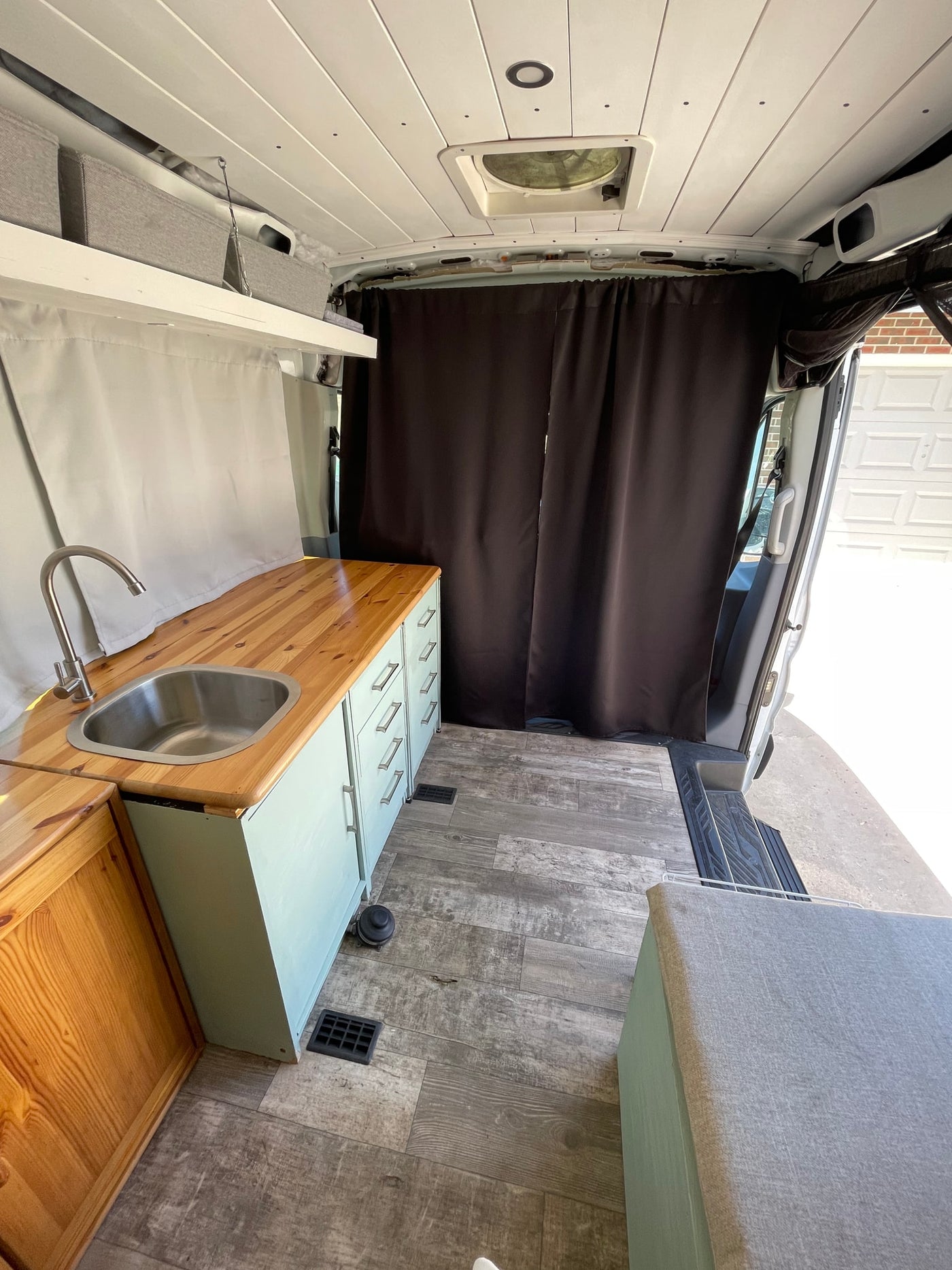 Inside this RV rental: a modern van conversion with a kitchen, sink, wood counter, floor, and ample storage. — photo 9