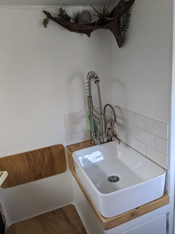 Modern sink area in an RV rental, featuring a pull-down faucet, white basin, and wooden details for compact living.