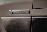 The metallic 'WINNEBAGO' emblem on the side of a modern RV, ready for your next rv rental adventure.