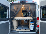 Rear view of an rv rental's interior with open doors, showing a mesh screen, bed, and storage. Perfect for camper van adventures.