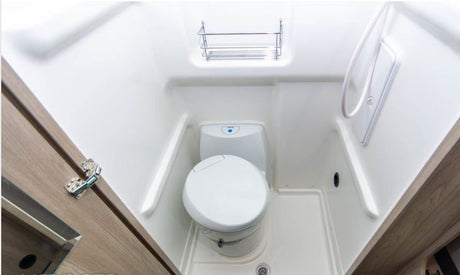 Compact RV rental bathroom features a toilet, shower, and storage rack. A practical wet bath design for travel.
