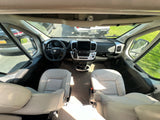 Spacious RV rental front cabin, featuring dashboard, steering wheel, and comfortable swivel seats with an outside view.