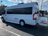 White Ultimate Toys camper van, ideal for RV rental, showcasing a rear StowAway cargo box in a sunny lot.