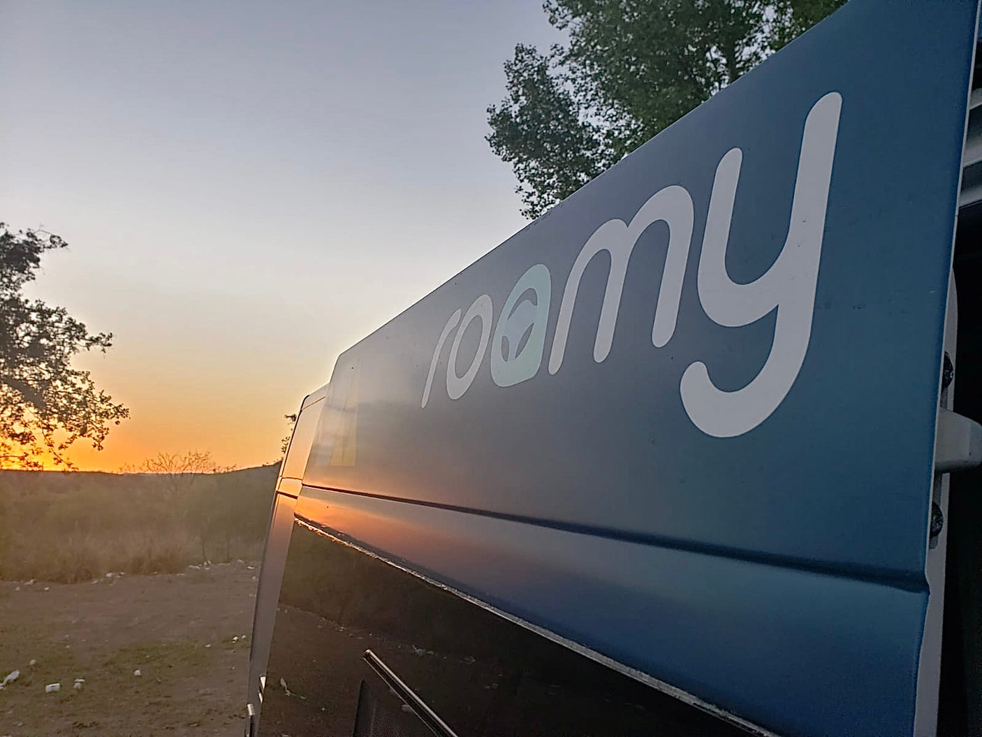 RV rental adventure at sunset. A "roomy" camper van parked outdoors, reflecting the golden hour.