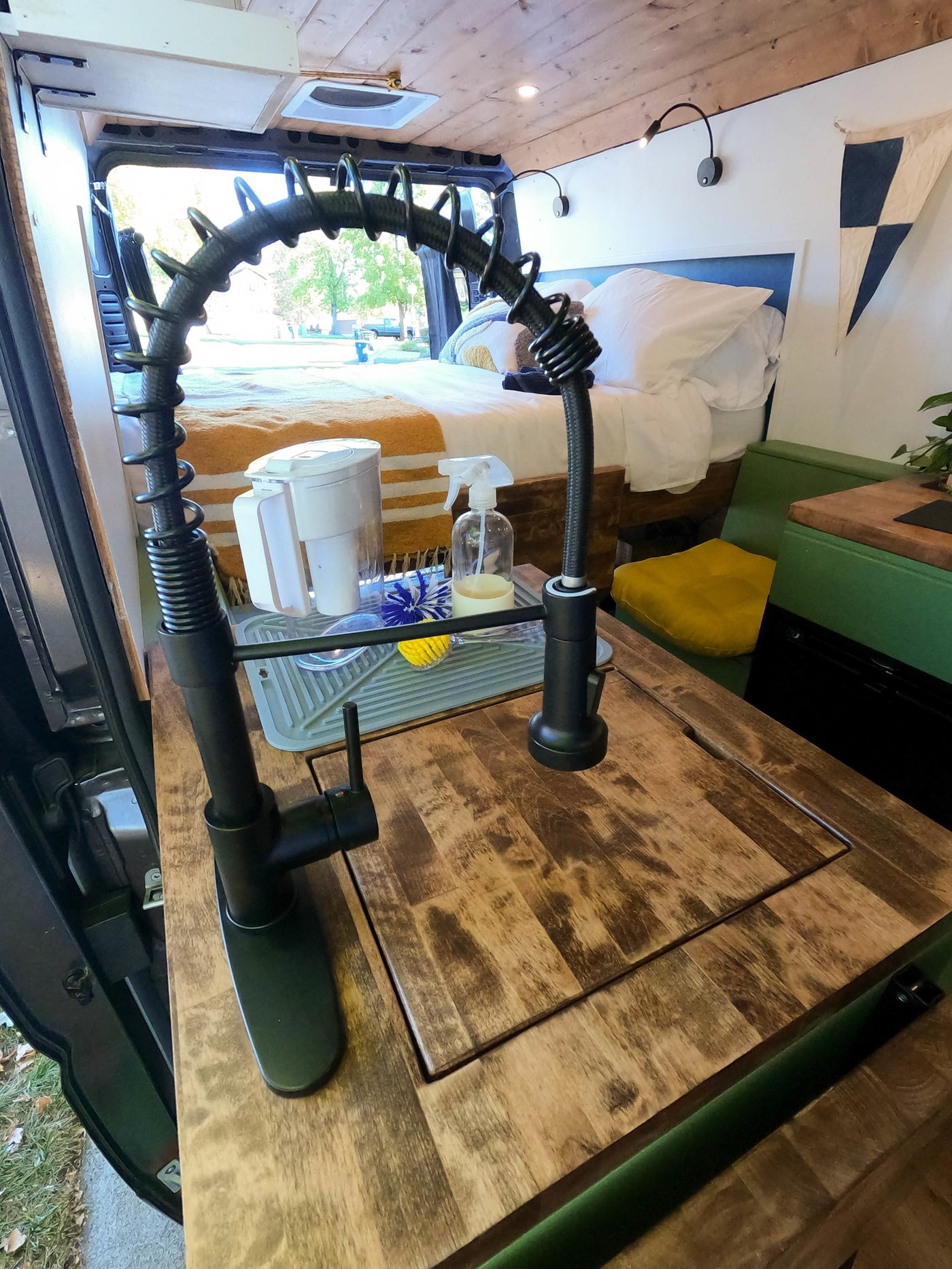 Cozy RV rental interior with a functional kitchen sink area, complete with a water filter, and a comfortable bed. — photo 19