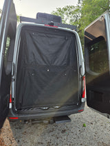 Rear of an RV rental camper van with doors open, revealing a black privacy screen. Features a roof AC unit and tow hitch.