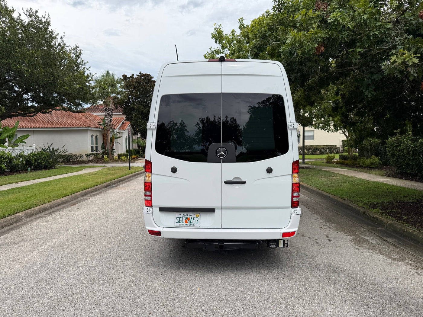Rear view of a white Mercedes-Benz Sprinter van on a residential street, featuring a Florida license plate. Ideal for an RV rental. — photo 4