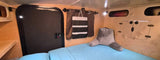 RV rental interior: cozy bed with back pillow, wood paneling, storage cubbies, and a door for your next camper adventure.