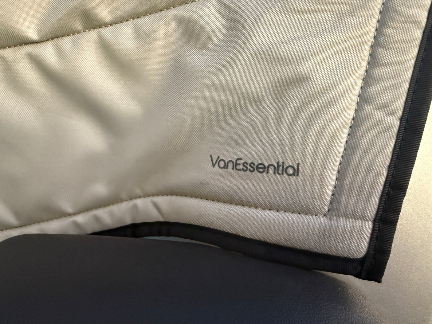 Close-up of VanEssential branded, light grey padded RV insulation, common in RV rental vehicles. Black trim is visible.