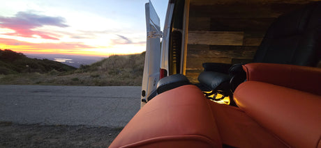 Golden hour relaxation: an rv rental with comfy seating, open to a stunning sunset, mountain, and lake view.