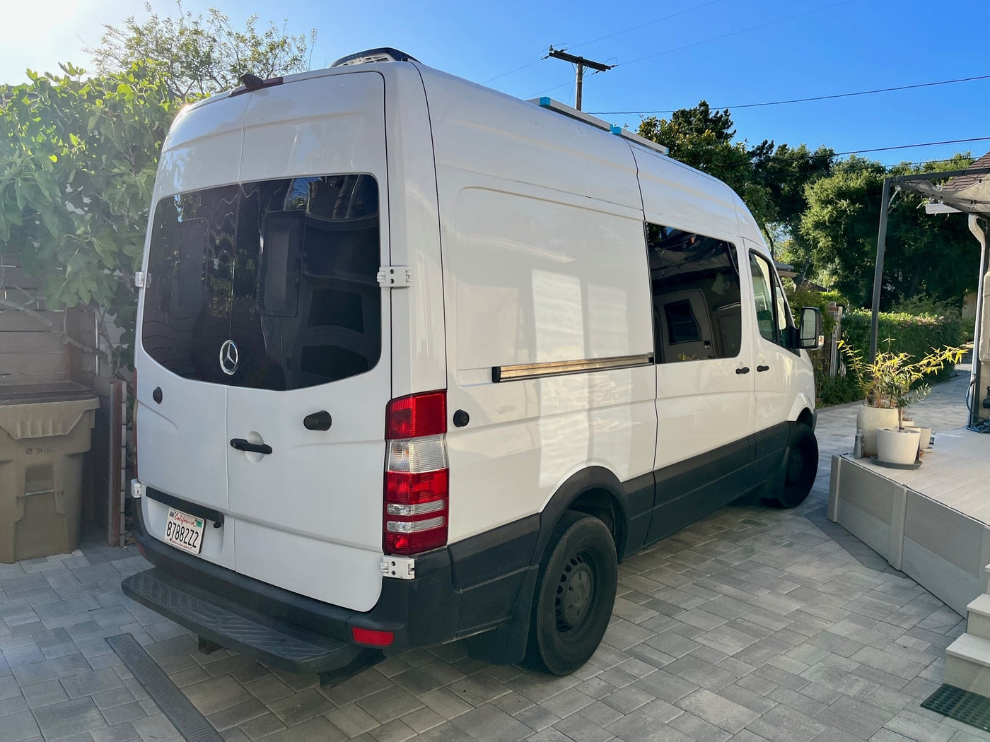 White Mercedes Sprinter camper van with roof unit, likely an RV rental, parked on a paved driveway. — photo 7