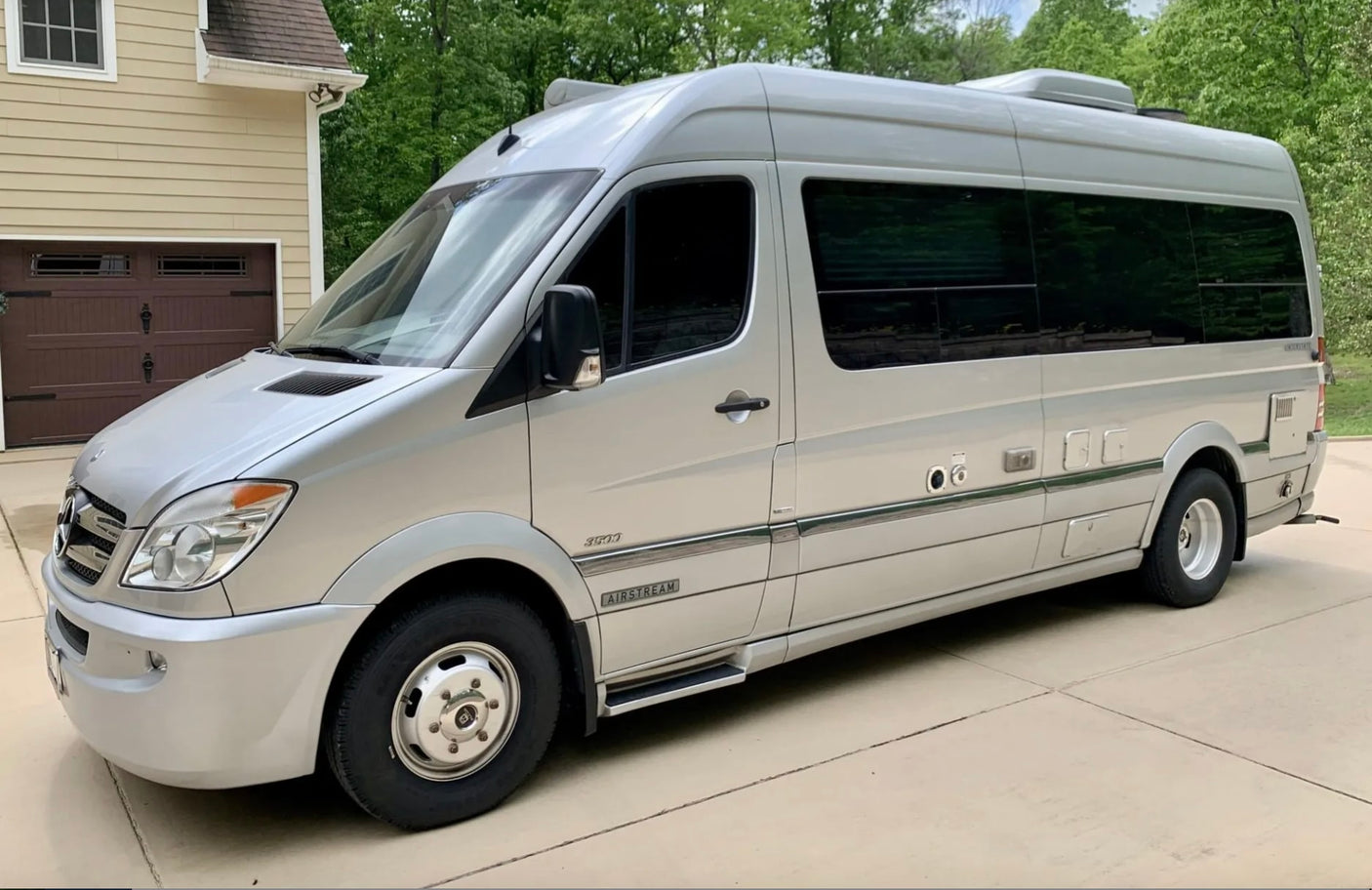 This silver Mercedes-Benz Sprinter Airstream RV rental is ready for adventure, parked on a sunny driveway.