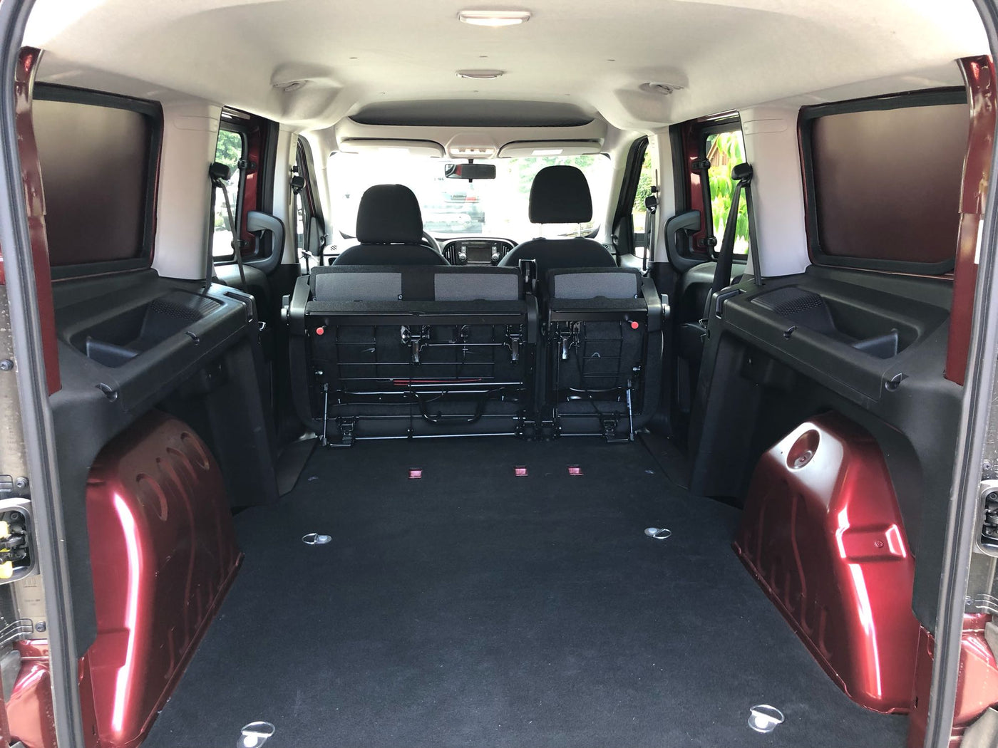 RV rental's spacious rear cargo area: folded seats, flat black floor, red interior panels, and tie-down points. — photo 12