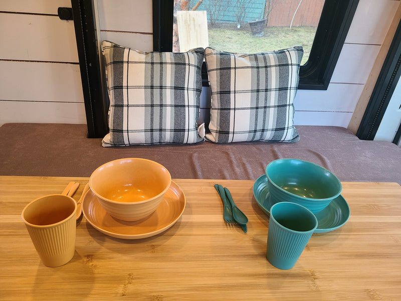 Cozy RV rental interior showcasing a dining setup for two: plaid pillows, yellow & teal dishware on a wood table. — photo 6