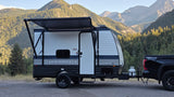 RV rental camping: A Springdale travel trailer hitched to a truck, parked in a scenic mountain setting with its awning extended.