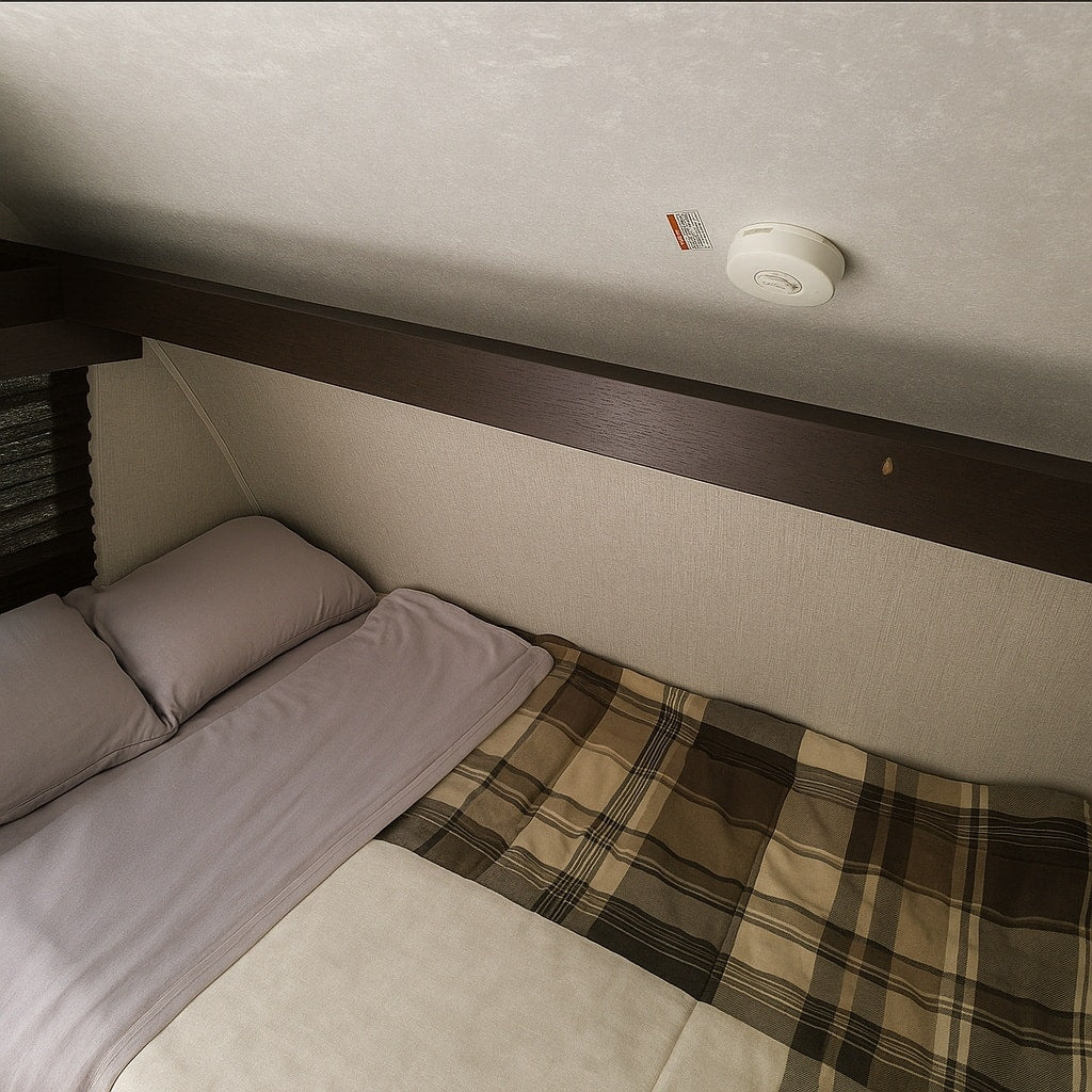 Inside an RV rental: a cozy sleeping area with a bed, plaid blanket, and smoke detector on the ceiling. — photo 20