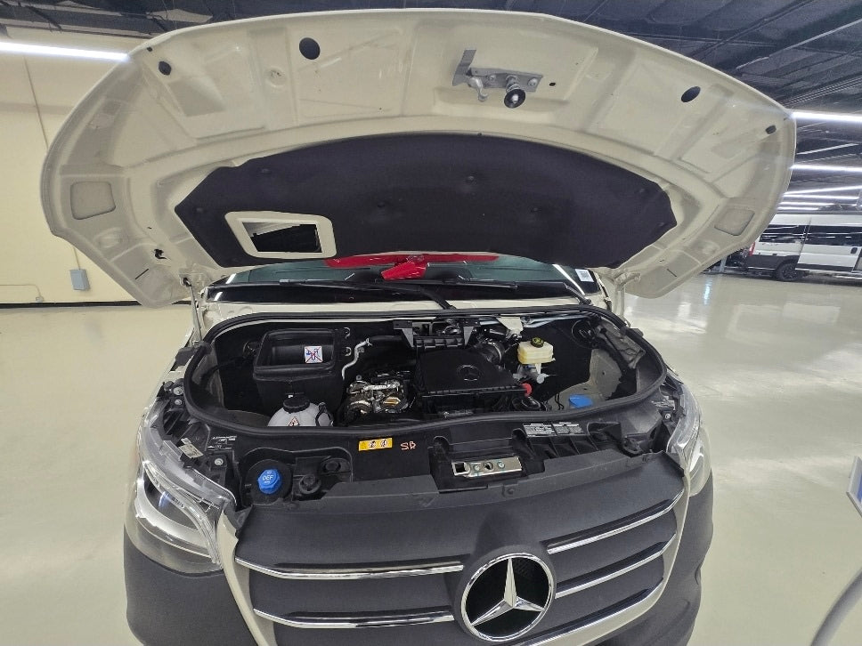 A white Mercedes-Benz RV rental van with its hood open, showing the engine bay. Essential pre-trip maintenance ensures a safe journey.