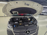 A white Mercedes-Benz RV rental van with its hood open, showing the engine bay. Essential pre-trip maintenance ensures a safe journey.