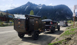 Ready for an rv rental journey: a rugged Off Grid overland trailer towed by a Jeep Gladiator, set against a stunning mountain backdrop.