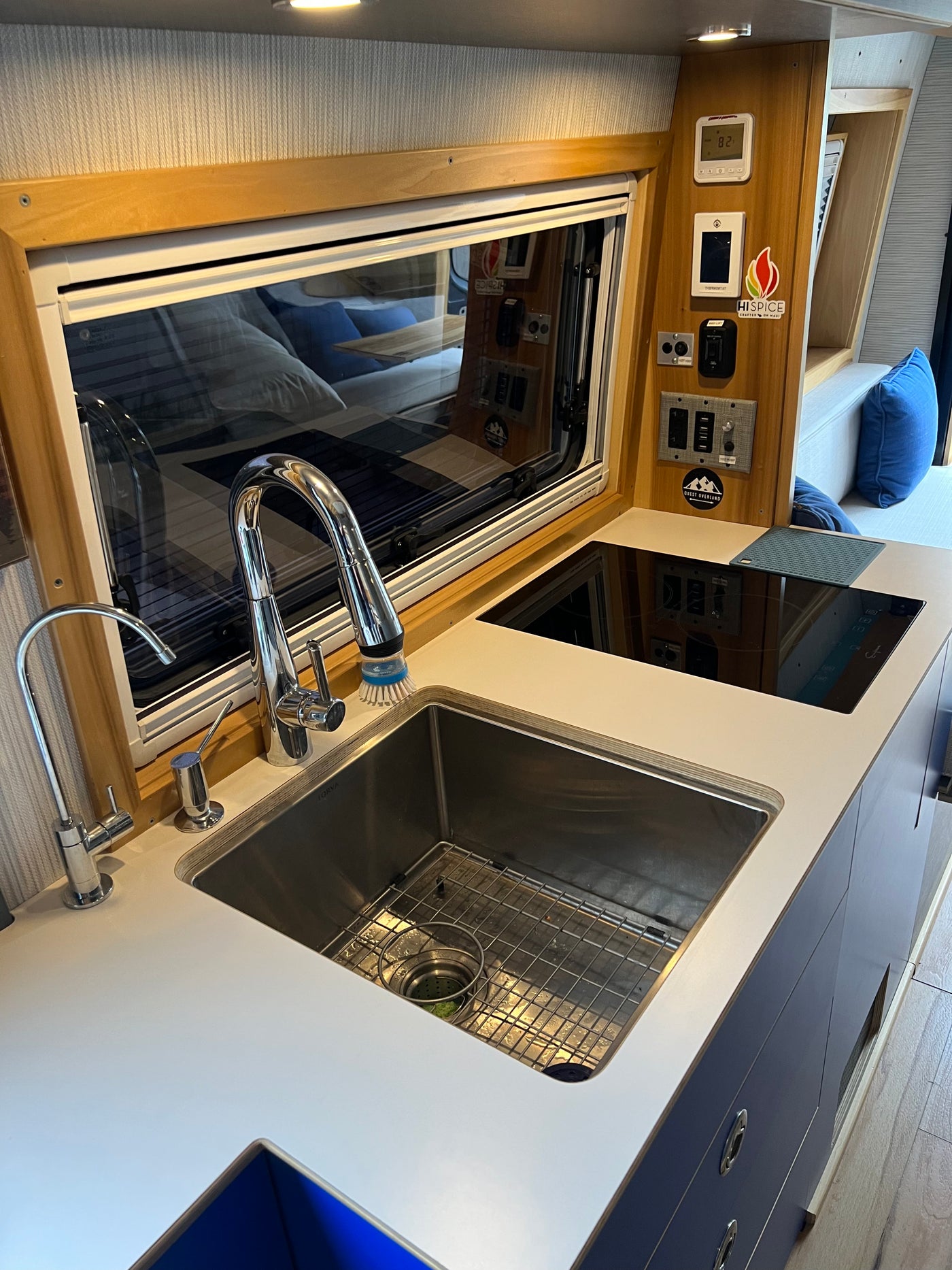 Experience comfort in our RV rental: a modern camper van kitchen with a stainless steel sink, dual faucets, and induction cooktop. — photo 5