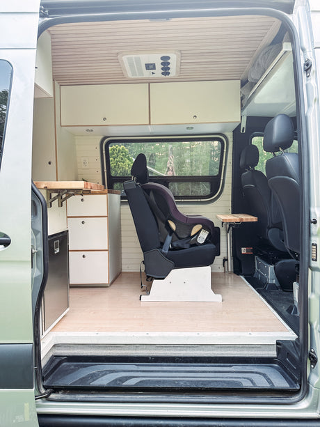 Inside an RV rental: a family-friendly camper van with child car seat, kitchenette, and passenger seating for road trip comfort.
