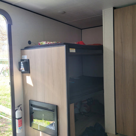 Cozy rv rental interior featuring built-in bunk beds, an electric fireplace, and a mounted fire extinguisher by the door.