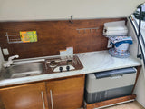 Fully equipped RV rental outdoor kitchen: integrated sink, gas stove, handy storage, and a pull-out NORCOLD fridge.