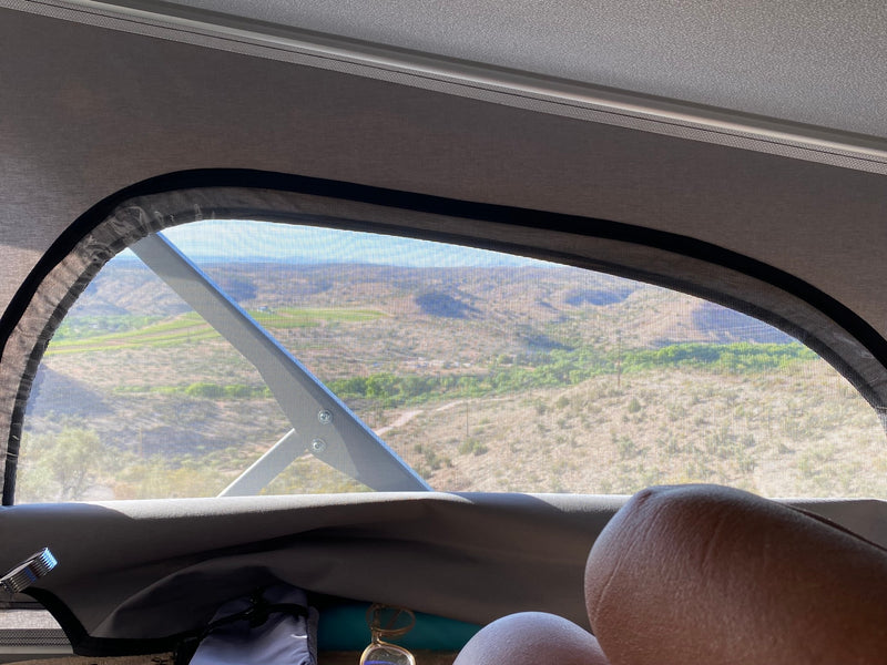 Relaxing in an RV rental, legs propped, viewing a vast desert landscape through the screened window. — photo 8
