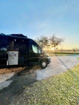 Black Ram ProMaster RV rental camper van parked at golden hour, side door open revealing a map. Ideal for van life adventures.