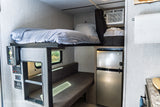 This RV rental interior offers a compact bunk bed, refrigerator, AC unit, and flexible dinette space.