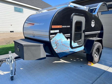 A sleek black "Modern Buggy" teardrop trailer with solar