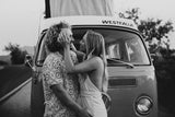 A loving couple embraces by a classic Westfalia camper van, ideal for a memorable RV rental road trip adventure.