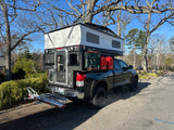Explore more with this truck camper RV rental. Black Toyota Tundra with pop-up overland rig & gear.