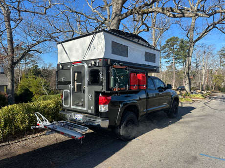 Explore more with this truck camper RV rental. Black Toyota Tundra with pop-up overland rig & gear.