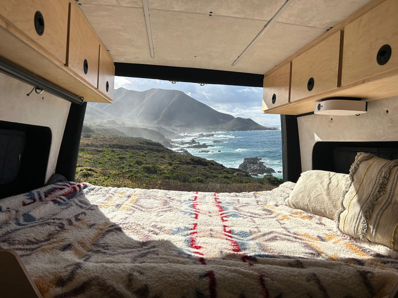  parked on a dirt road with a vibrant sunset and mountains.|RV rental van parked on a scenic mountain road — photo 4