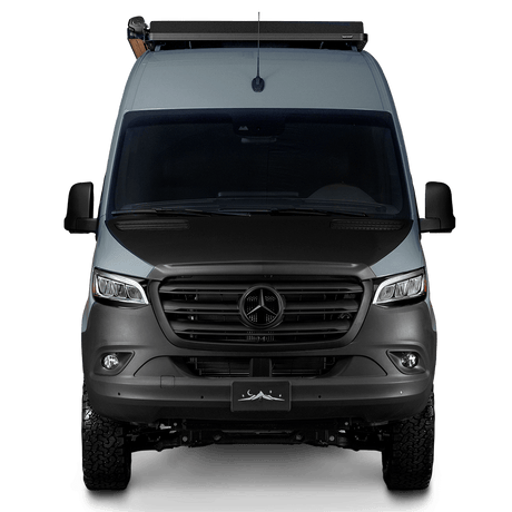 Frontal view of a sleek gray Mercedes-Benz Sprinter camper van with a roof rack and off-road tires. Great for rv rental.