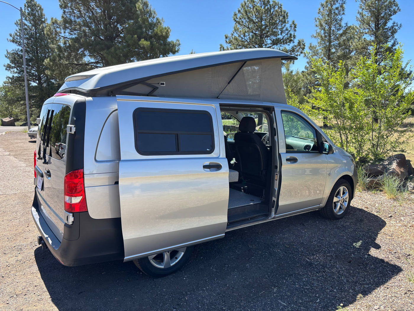Silver pop-top camper van with open door, parked outdoors. Ready for your next rv rental adventure! — photo 4