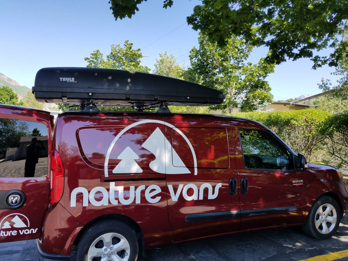 Maroon 'nature vans' van with a Thule roof box, ideal for RV rental adventures.