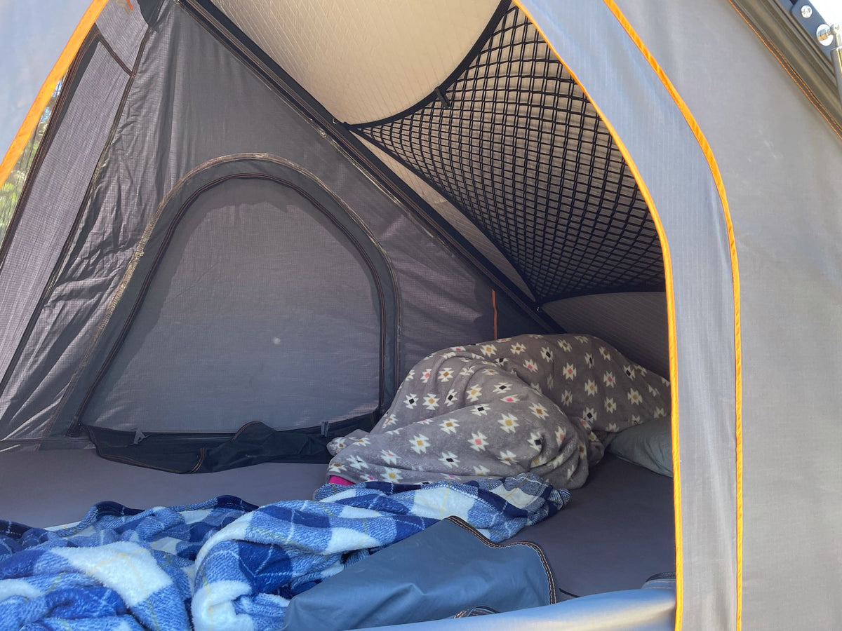 Cozy interior of a roof-top tent with blankets, pillows & storage net, perfect for your RV rental adventure. — photo 11