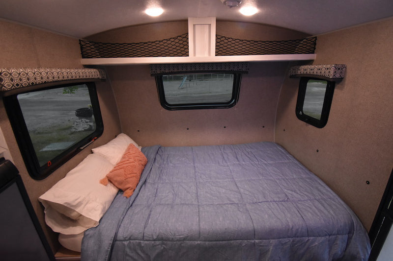 Cozy interior of an RV rental: a compact bedroom with a bed, windows, and storage nets, ideal for travel. — photo 11