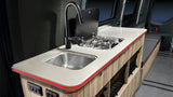 RV rental kitchen: compact design with sink, 2-burner stove, and illuminated counter. Ideal for mobile adventures.