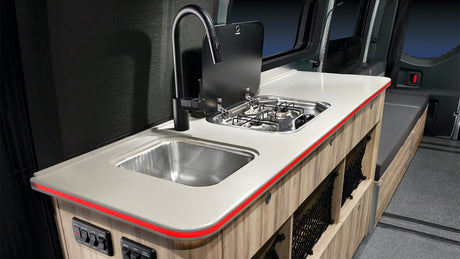 RV rental kitchen: compact design with sink, 2-burner stove, and illuminated counter. Ideal for mobile adventures.